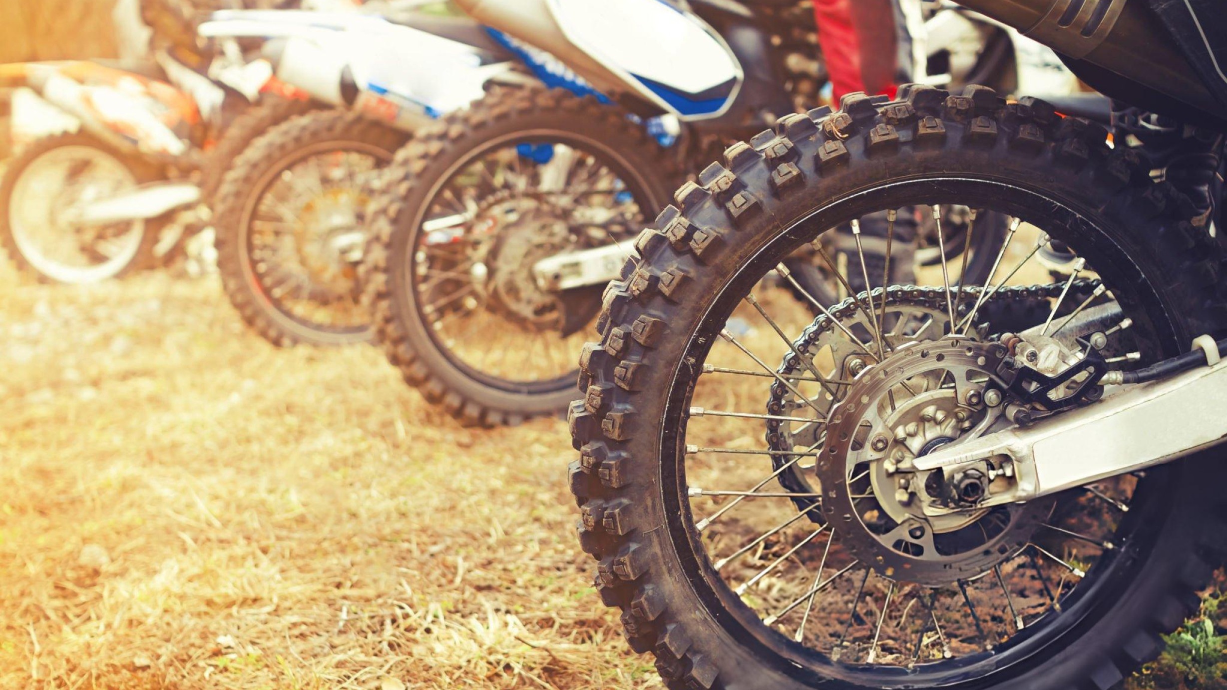 Hero image of a dirt bike rear wheel with chain and sprockets, overlay showing gear ratio calculation and terrain icons
